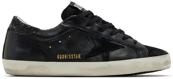 Golden Goose women’s Superstar sneaker with black leather upper, glitter heel tab, silver star, and distressed sole.