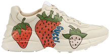 Gucci women’s Rhyton sneaker in white leather featuring oversized Gucci Strawberry graphic and chunky retro sole.

