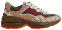 Gucci Wmns GG Rhyton sneaker in beige GG Supreme canvas with brick red Gucci logo and thick vintage-style rubber sole.

