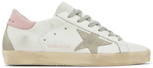 Golden Goose Superstar women’s sneaker in white leather with pink heel tab and distressed rubber sole.